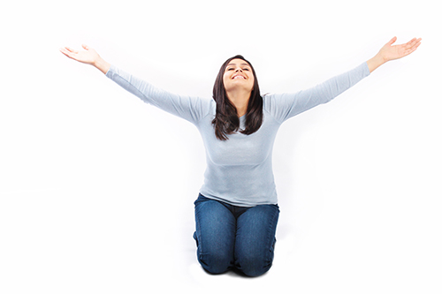 Young woman on her knees with arms raised up