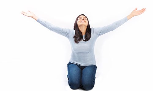 Young woman on her knees with arms raised up